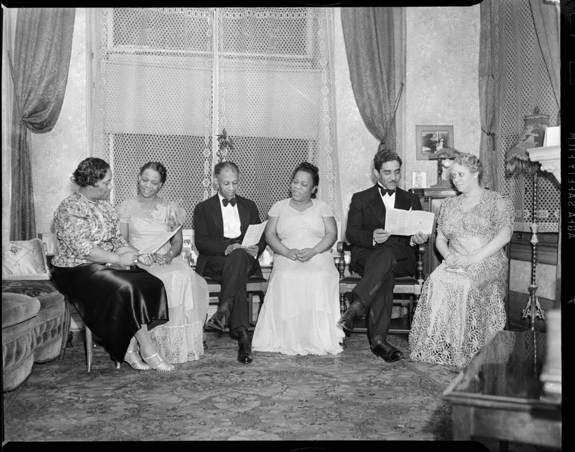 Image credit: ​​National Association of Negro Musicians board members, 1941 © Carnegie Museum of Art, Charles “Teenie” Harris Archive. Description: Black and white photo of three pairs of Black musicians in formal dress, seated in front of a tall lace curtain. Each pair is looking at a page of sheet music.